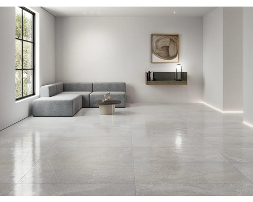 Pièce lumineuse avec carrelage au sol, canapé, table et étagère murale