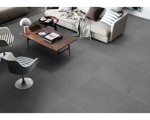 Salon lumineux avec carrelage gris, canapé et deux chaises