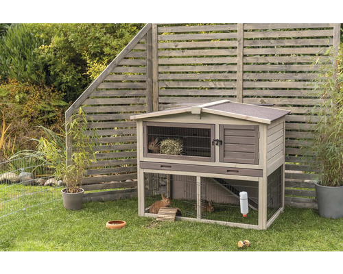 Clapier à lapin en bois indépendant à deux étages avec enclos extérieur dans le jardin.