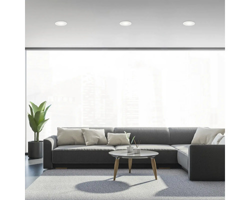 Wohnzimmer mit grauer Couch, Teppich und Deckeneinbaustrahlern für eine helle Atmosphäre