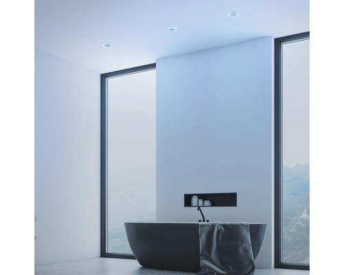 Salle de bains moderne avec baignoire îlot, serviette et spots encastrés au plafond.