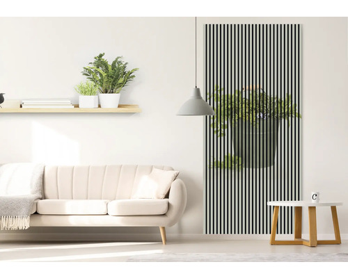 Salon avec canapé, table et décoration murale avec motif de plante derrière des rayures noires