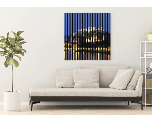 Art mural décoratif avec un motif de paysage urbain derrière des lignes verticales au-dessus d''un canapé dans un salon.