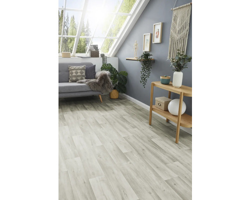 Heller Raum mit Laminatboden, Sofa, Tisch und Dekorationen unter einem Dachfenster