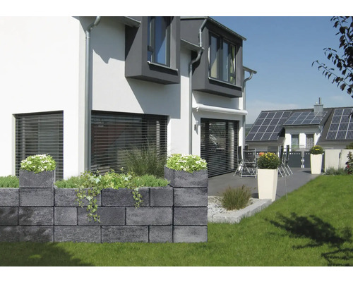 Garten mit Mauer aus Betonsteinen und Bepflanzung vor einem Wohnhaus