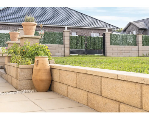 Vue de jardin avec bacs à plantes, mur en blocs de béton et clôture avec écran d''intimité