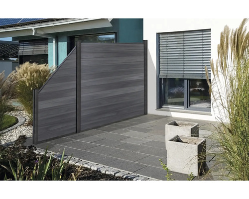 Holzzaun im Gartenbereich mit Pflanzen und Pflastersteinen