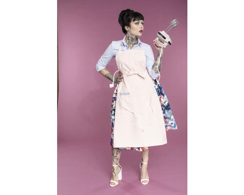 Femme avec des tatouages, tablier et mixeur à main sur fond coloré