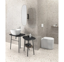 Salle de bains avec lavabo, miroir et toilettes devant un mur et un sol mouchetés