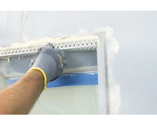 Ein Arbeiter befestigt eine Putzschiene an einer Wand.