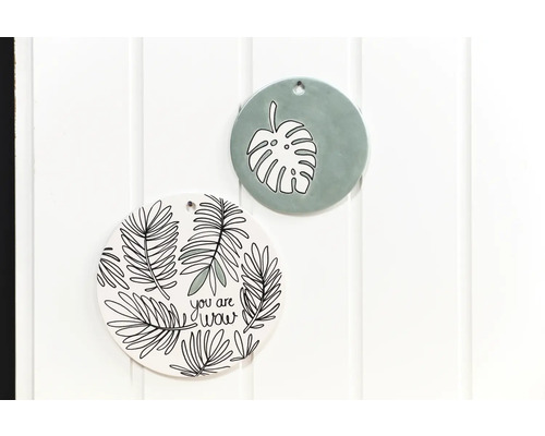 Zwei dekorative Wandteller mit Pflanzenmotiven an einer weißen Wand