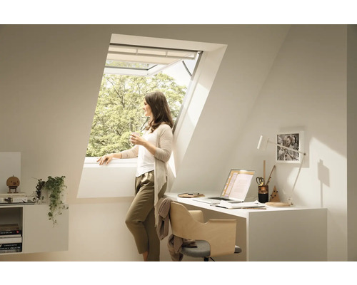 Heller Dachbodenraum mit Dachfenster, Schreibtisch und einer Frau am Fenster