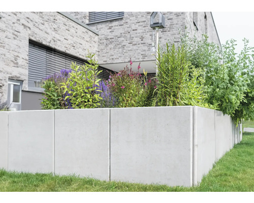 Jardinière surélevée en béton avec des plantes devant une maison