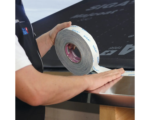 Une personne utilise du ruban adhésif SIGA Twinet sur une surface.