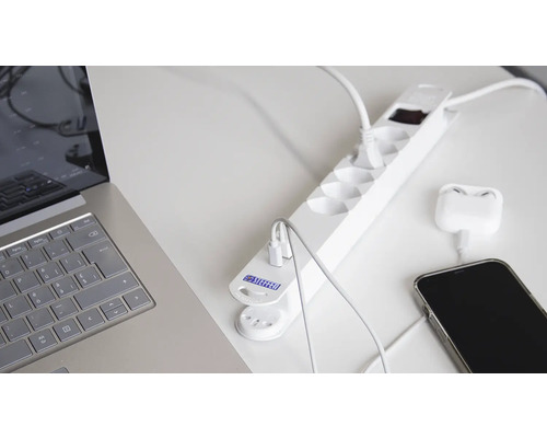 Multiprise avec ports USB, ordinateur portable et téléphone portable sur un bureau.