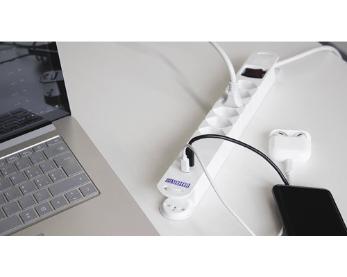 Steckdosenleiste mit angeschlossenen elektronischen Geräten auf einem Tisch