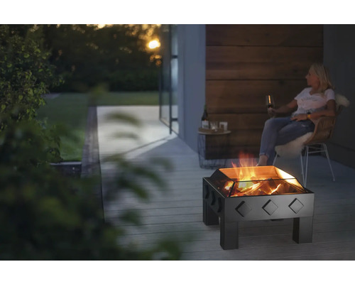 Gartenszene mit Feuerstelle, brennendem Holz und sitzender Person