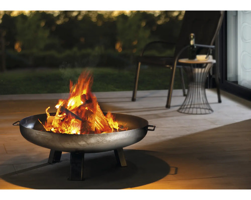Brasero avec du bois qui brûle sur une terrasse avec des sièges