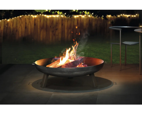 Feuerschale mit brennendem Holz im Gartenbereich.