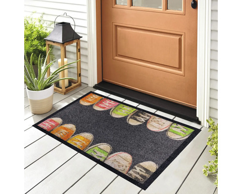 Fussmatte mit Schuhmotiv vor einer Haustür