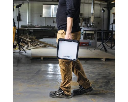 Une personne porte une lampe de travail Scangrip dans un atelier.