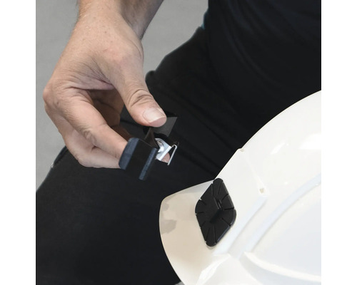 Personne fixant un support de lampe frontale sur un casque de chantier.