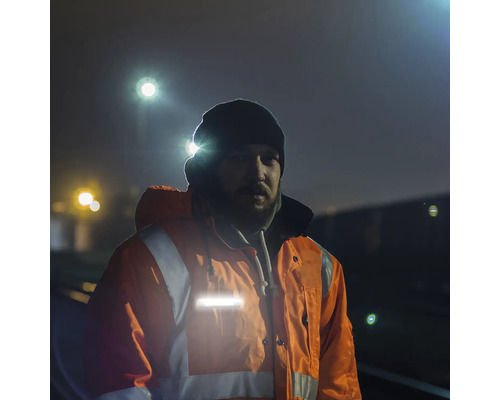 Homme portant une veste de travail réfléchissante et une lampe frontale dans l''obscurité.