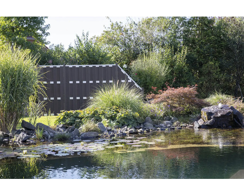 Gartenszene mit Teich, Pflanzen und Zaun