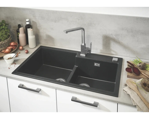 Évier de cuisine avec deux bacs et robinetterie sur un plan de travail.
