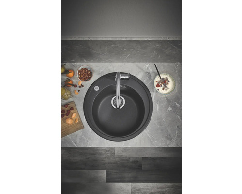 Vue de dessus d''un évier de cuisine rond avec robinet, entouré d''aliments sur un plan de travail