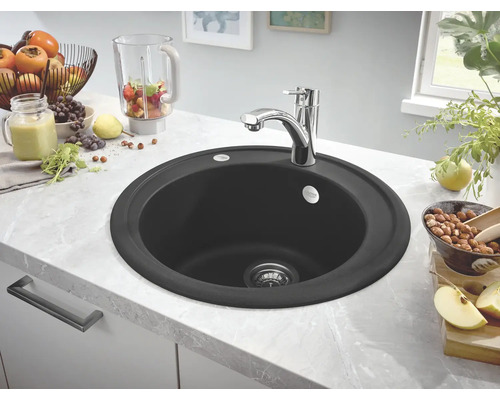 Scène de cuisine avec un évier rond et un robinet sur un plan de travail.