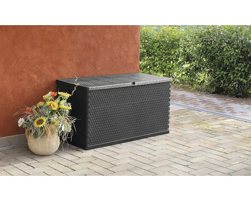 Aufnahme einer schwarzen Gartenbox auf einer Terrasse neben einem Gebäude und einer Blumenvase.