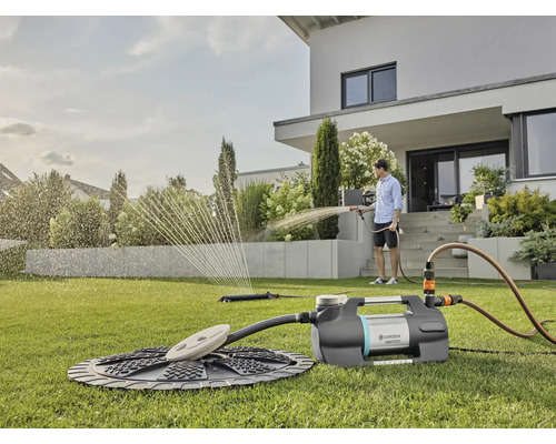 Scène d''irrigation de jardin avec pompe, arroseur et personne arrosant avec un tuyau d''arrosage