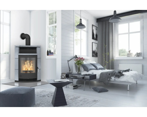 Chambre lumineuse avec poêle, lit et fenêtres pour une atmosphère conviviale.