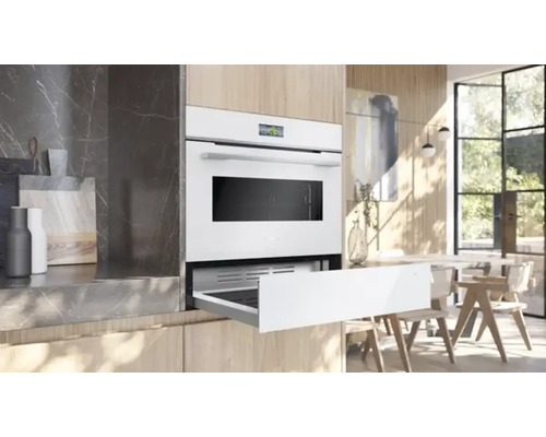 Four encastrable dans une cuisine moderne avec un tiroir ouvert pour les accessoires.