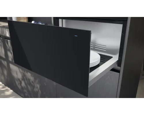 Un chauffe-assiettes est intégré dans une cuisine moderne avec des armoires et des tiroirs foncés