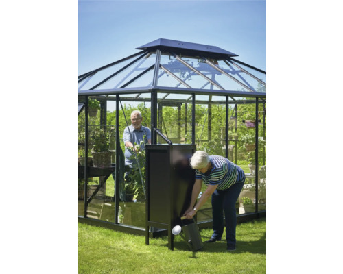Gewächshaus mit zwei Personen und einer Gießkanne im Garten.