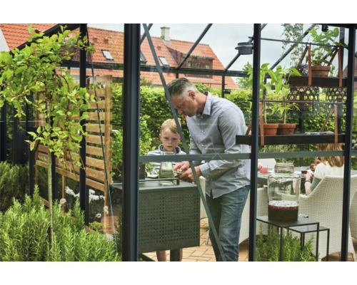 Famille dans une serre avec des plantes et des meubles de jardin.