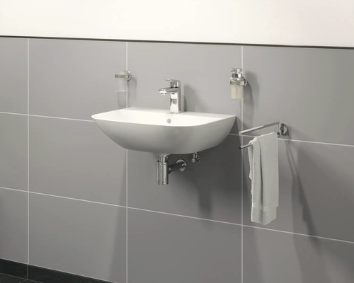 Lavabo en céramique avec robinetterie, distributeur de savon et porte-serviettes sur un mur carrelé