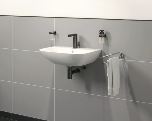 Wandwaschbecken mit Armatur, Seifenspender, Zahnputzbecher und Handtuchhalter im Badezimmer.