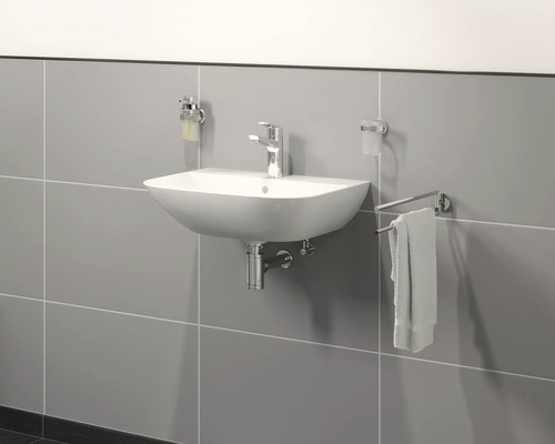 Lavabo en céramique avec robinet, distributeur de savon, gobelet à brosse à dents et porte-serviettes dans la salle de bain