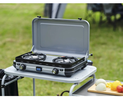 Réchaud à gaz double sur une table de camping à l''extérieur avec couvercle ouvert.