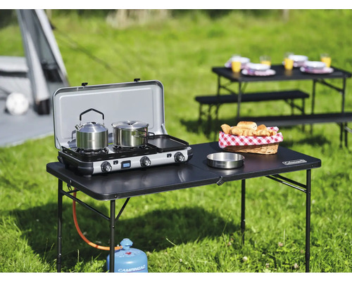 Scène de camping avec réchaud à gaz, table et vaisselle à l''extérieur