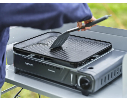 Barbecue de table de camping avec plaque de gril et personne avec une spatule