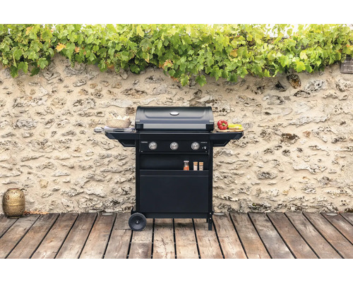 Barbecue à gaz foncé avec trois brûleurs sur une terrasse en bois