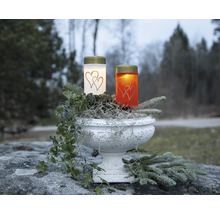 Deux bougies funéraires avec motif de cœur dans une jardinière avec décoration.