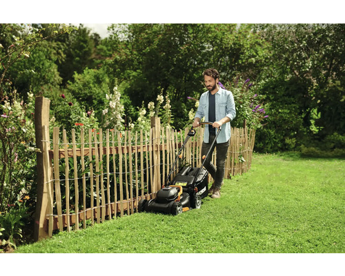 Homme tondant la pelouse avec une tondeuse à gazon dans un jardin