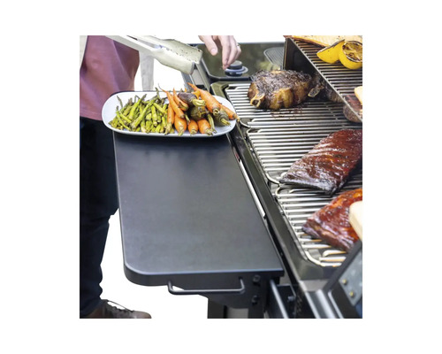 Scène de barbecue avec des légumes, de la viande et des côtes levées sur le gril et une assiette d''asperges et de carottes grillées sur une étagère.