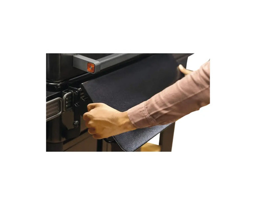 Une personne déplie une table de barbecue sur un barbecue en métal