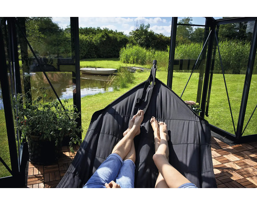 Personen entspannen in einer Hängehöhle in einem Gewächshaus mit Blick auf einen See